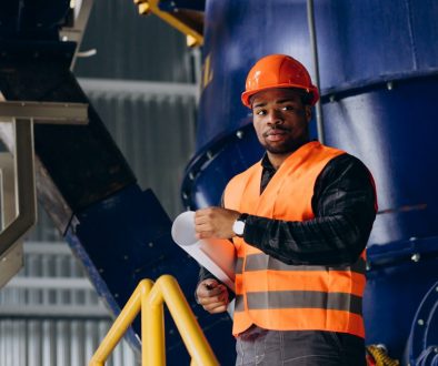 African american worker standing in uniform wearing a safety hat in a factory